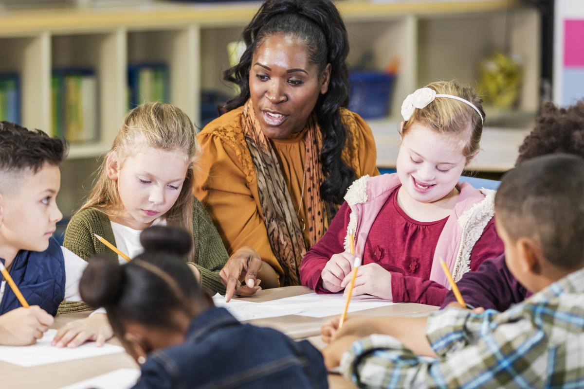 Illinois Special Education Teacher Tuition Waiver Program - Teacher and young students at a table working together on writing