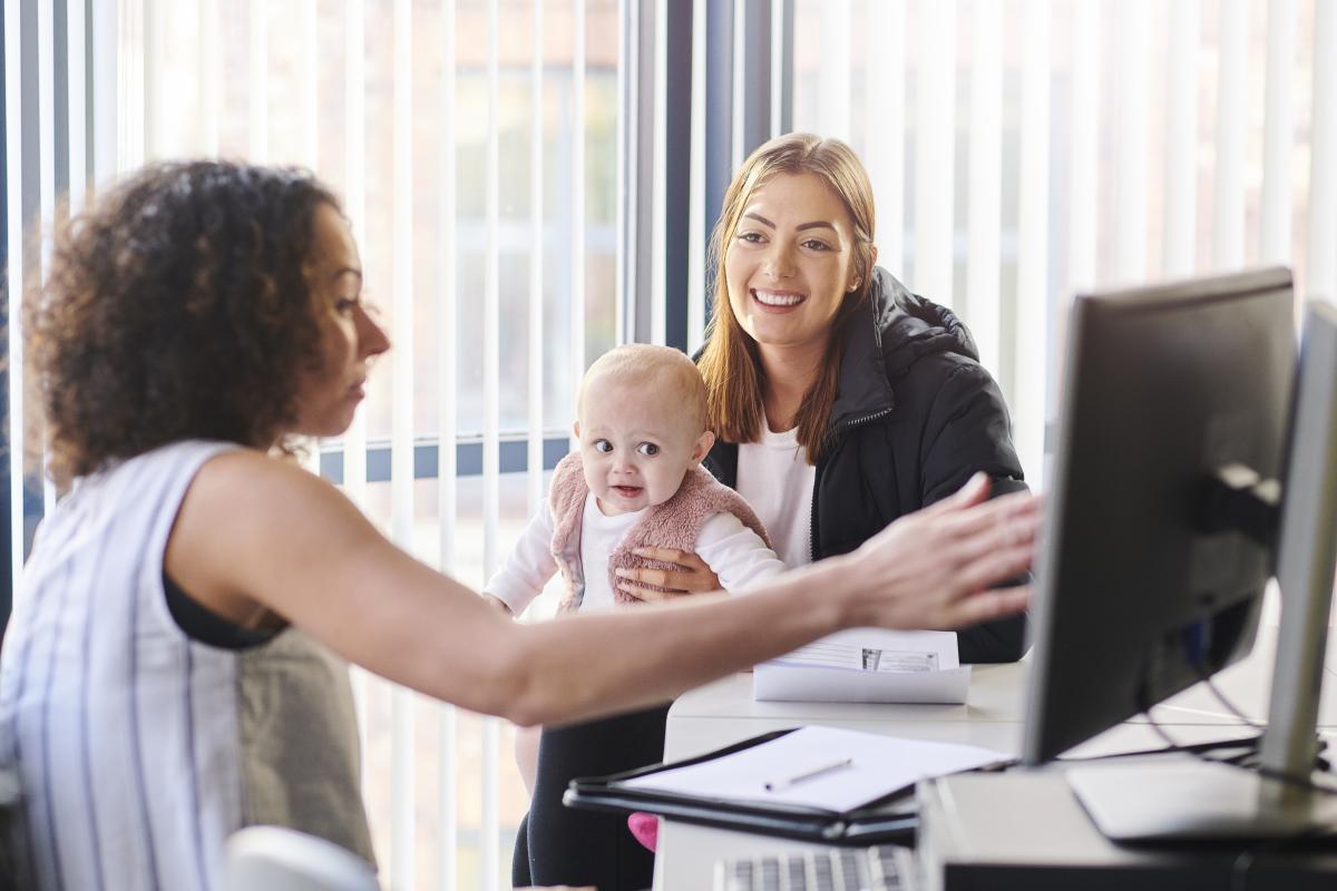 School and Municipal Social Work Shortage Loan Repayment Program - Professional showing something on a computer screen to a mother and baby