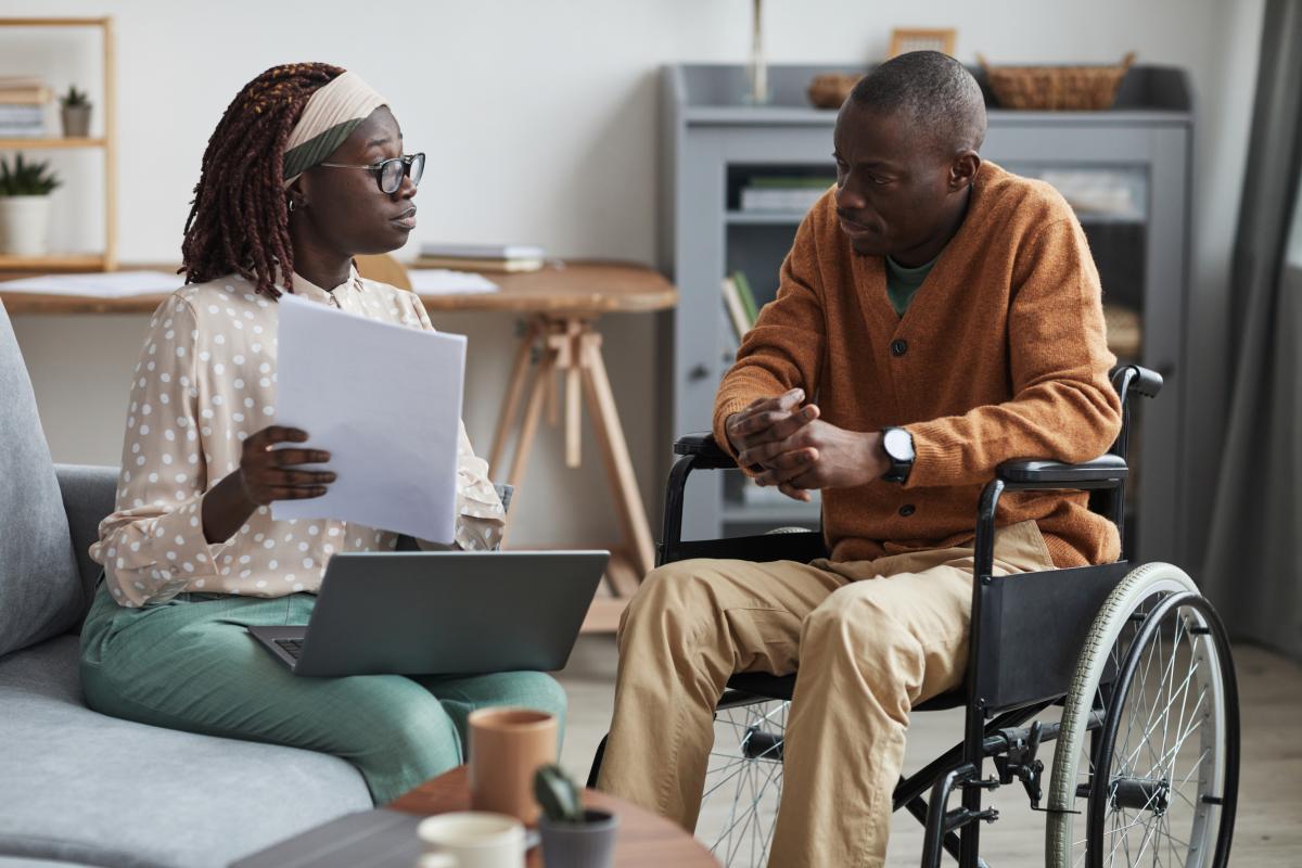 School and Municipal Social Work Shortage Loan Repayment Program - Professional looking over paperwork with a man in a wheelchair