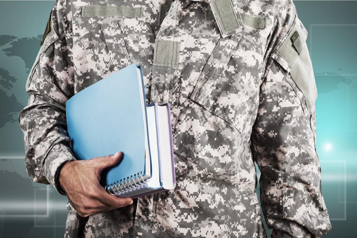 Person in Military fatigues holding books and a notebook