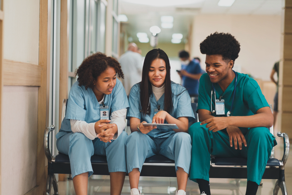 3 nurses sitting on an office couch looking at a chart together