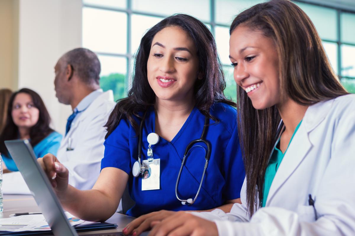 Two nurses reviewing records on a laptop
