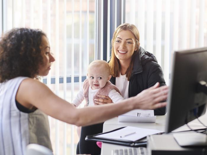 School and Municipal Social Work Shortage Loan Repayment Program - Professional showing something on a computer screen to a mother and baby