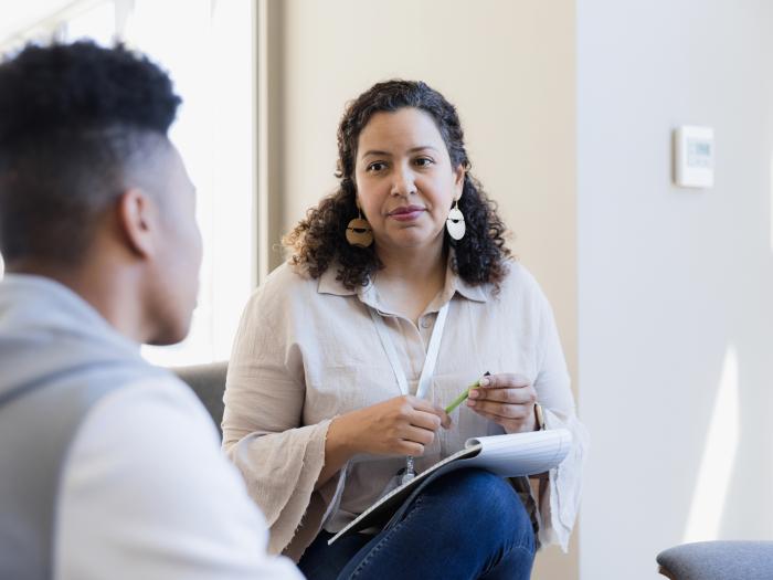 School and Municipal Social Work Shortage Loan Repayment Program - Professional with a notepad conversing with a young adult