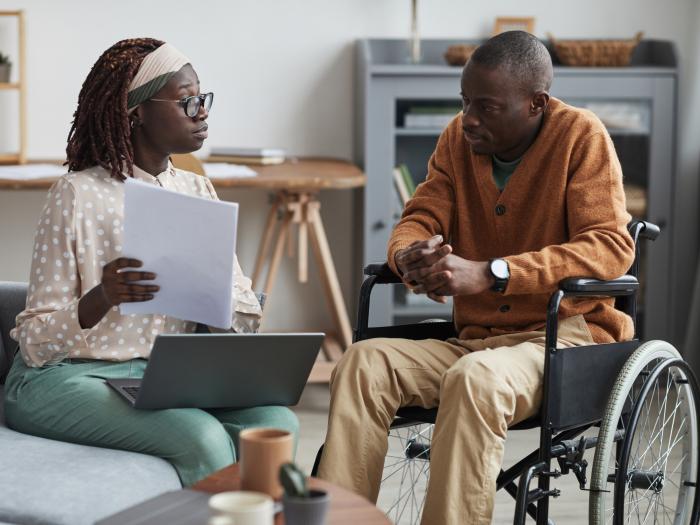School and Municipal Social Work Shortage Loan Repayment Program - Professional looking over paperwork with a man in a wheelchair