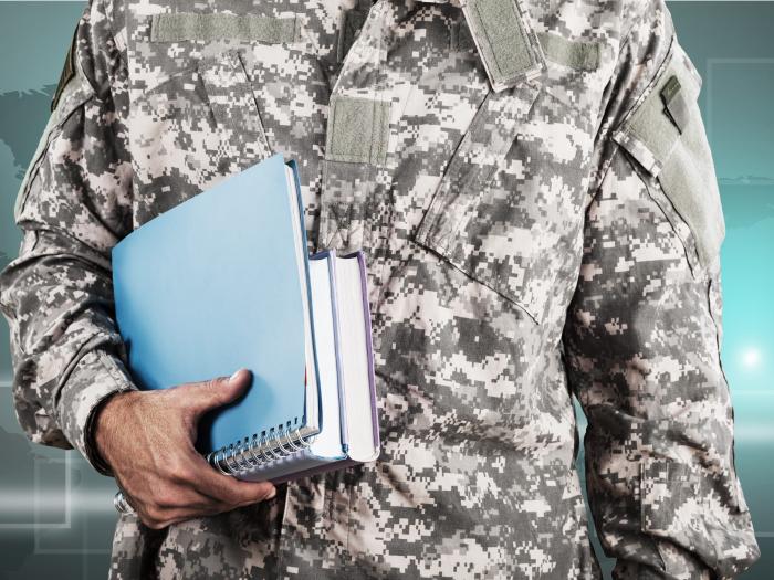 Person in Military fatigues holding books and a notebook