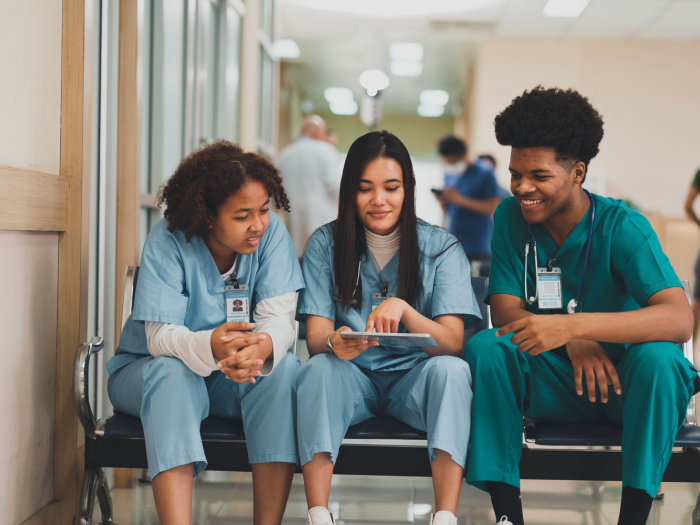 3 nurses sitting on an office couch looking at a chart together